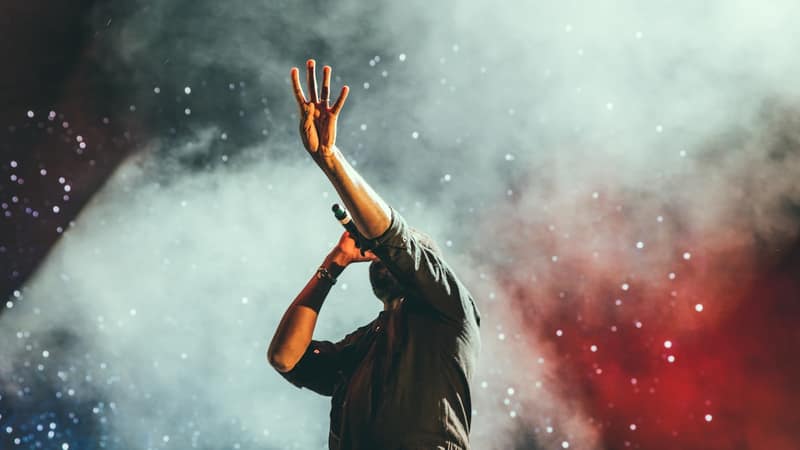 Concert stage with dramatic purple and gold lighting and massive crowd of fans